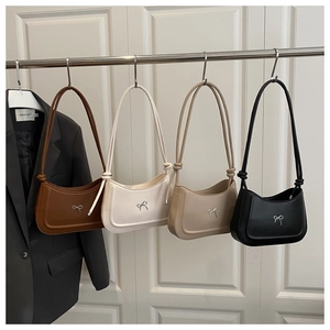 Detail view of stylish leather underarm bags with silver bow accents in four colors