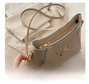 Detail view of smooth metal zipper and elegant metal bow decoration on beige handbag