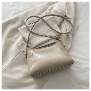 Dettaglio della borsa a tracolla beige crema in pelle lucida con fibbie dorate