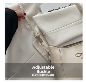 Detail of adjustable gold buckle and cream leather strap on minimalist shoulder bag