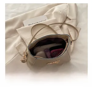 Interior capacity of beige shoulder bag showing makeup and power bank storage