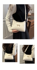 Detail of off-white shoulder bag featuring a decorative golden bow metallic buckle