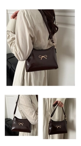 Detail of dark brown glossy patent leather bag with a golden bow metal buckle accessory