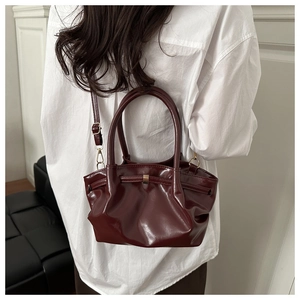 Detail of burgundy glossy PU leather tote bag showing twin handles and gold hardware