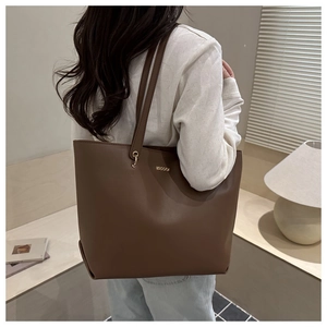 Detail view of large brown leather tote bag with elegant gold metal decorative hardware
