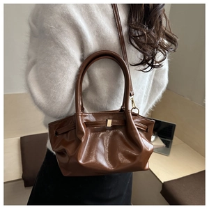 Detail of a brown pleated tote bag featuring shiny synthetic leather and golden buckle