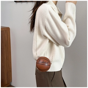 Detalle del bolso bandolera creativo con forma de baloncesto, cadena dorada y texto