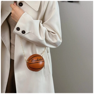 Detalle de bolso bandolera con forma de baloncesto, cadena dorada y textura de piel granulada