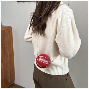 Detalle del bolso rojo con forma de baloncesto y cadena dorada usado por una modelo