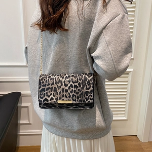 Fashionable leopard print shoulder bag with gold chain strap worn by a model