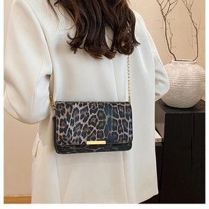 Detail of leopard print crossbody bag with gold chain strap on a white blazer model