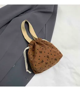 Detail of brown corduroy bucket bag with black heart patterns and drawstring closure