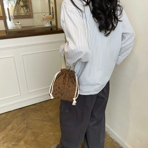 Brown corduroy bucket bag with black bow patterns and white drawstring cord strap
