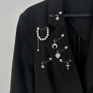 Detailed close-up of fashion silver safety pin set with pearls and charms on a black blazer