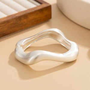 Détail d'un bracelet vague argenté massif avec texture brossée mate sur support bois