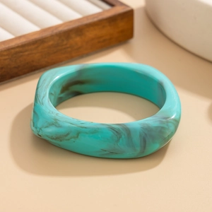 Gros plan sur un bracelet jonc épais en résine marbrée turquoise au design irrégulier
