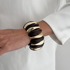 Detail of luxury gold and dark brown resin link stretch bracelet on female wrist