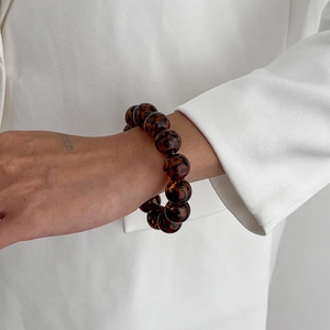 Detail of tortoise shell patterned acrylic beads on a stretch bracelet worn on wrist
