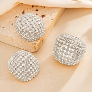 Detail of silver dome stud earrings with woven bead texture on natural stone and silk
