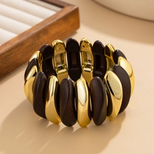 Close-up of pebble-shaped gold and dark brown wood texture modules on a wide stretch bracelet