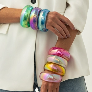 Dettaglio di bracciali in resina iridescente con finitura metallica colorata al polso