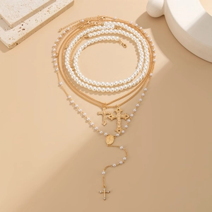 Detail of layered gold necklaces with pearl strands, cross pendants and a holy medal