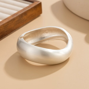 Detail view of a matte silver wavy wide cuff bracelet with a modern minimalist hinge design