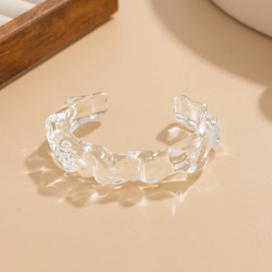 Macro detail of a transparent open bangle with unique irregular wavy texture and icy finish