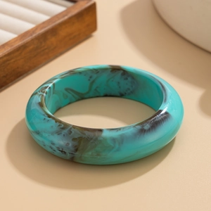 Detailed view of turquoise resin bangle with brown marble texture and polished finish