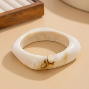 Detail view of a thick irregular resin bangle with white and brown marble texture