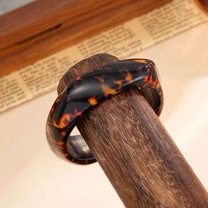 Close-up of irregular tortoiseshell resin bangle on a wooden display stand