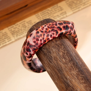 Close-up of wide leopard print resin bangle with high-gloss finish and tortoiseshell pattern