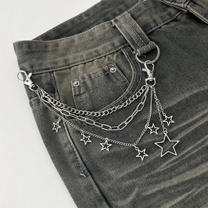 Silver multilayered metal waist chain with star pendants on distressed denim jeans