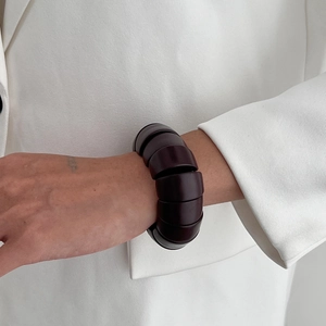 Détail d'un bracelet chunky en résine sombre porté avec une veste de costume blanche