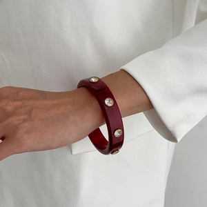 Détail du bracelet large en résine bordeaux avec cristaux sertis de dorure
