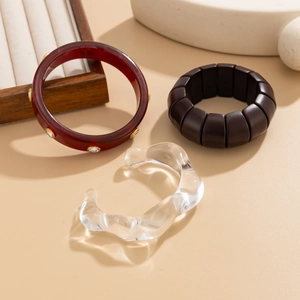 Détail de bracelets empilés avec résine bordeaux, cristaux et motifs carrés de couleur marron