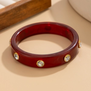 Détail d'un jonc vintage en résine bordeaux avec cristaux étincelants sertis d'or