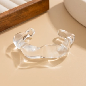 Détail d'un bracelet acrylique ondulé transparent avec réfraction élégante