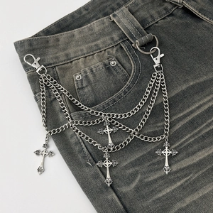 Detail view of gothic multilayer metal chains with vintage cross pendants on denim pants