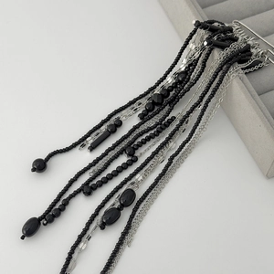 Detail of beaded tassels and silver chain brooch on grey velvet jewelry tray