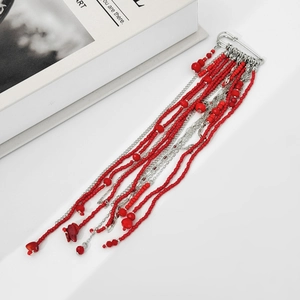 Détail de la broche épingle avec perles rouges et longues chaînes à pompons argentées