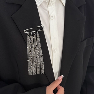 Détail d'une broche argentée avec perles et franges métalliques sur un costume noir