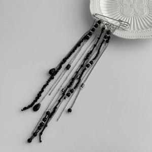Detail of gothic style brooch with long silver metal tassels and black crystal beads