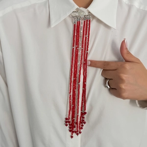 Gros plan d'une broche épingle avec longues perles rouges et glands en argent