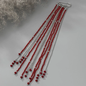 Détail d'une broche à pompons vintage avec perles rouges facettées et chaînes argentées