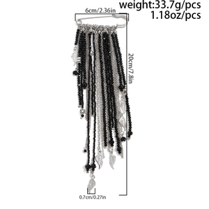 Detail view of long tassel safety pin brooch with black beads and silver wing charms