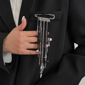 Détail d'une broche épingle vintage avec de longues franges de perles noires sur costume