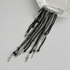 Detail of vintage gothic brooch with black beads, silver fringe chains and feather charms