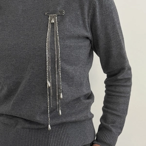 Vue détaillée de la broche à franges argentées avec pendentifs gouttes sur maille grise