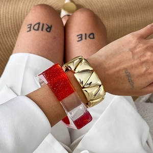 Bracelet géométrique doré et jonc en résine pailletée rouge porté par le mannequin